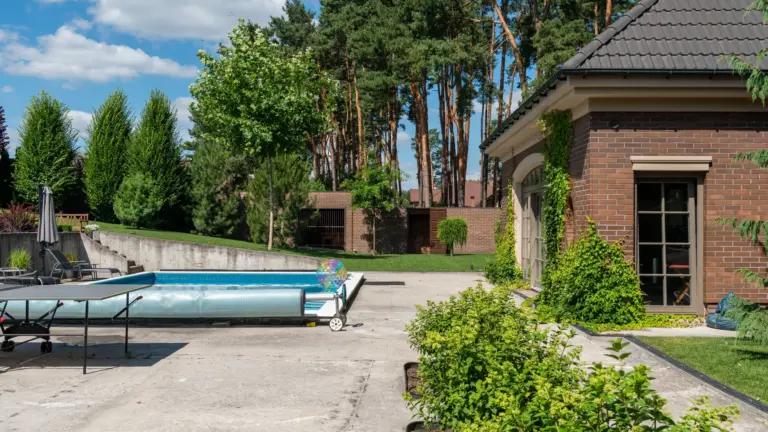 Gartenpool mit aufgerollter Solarabdeckung auf Wickelrolle am Beckenrand